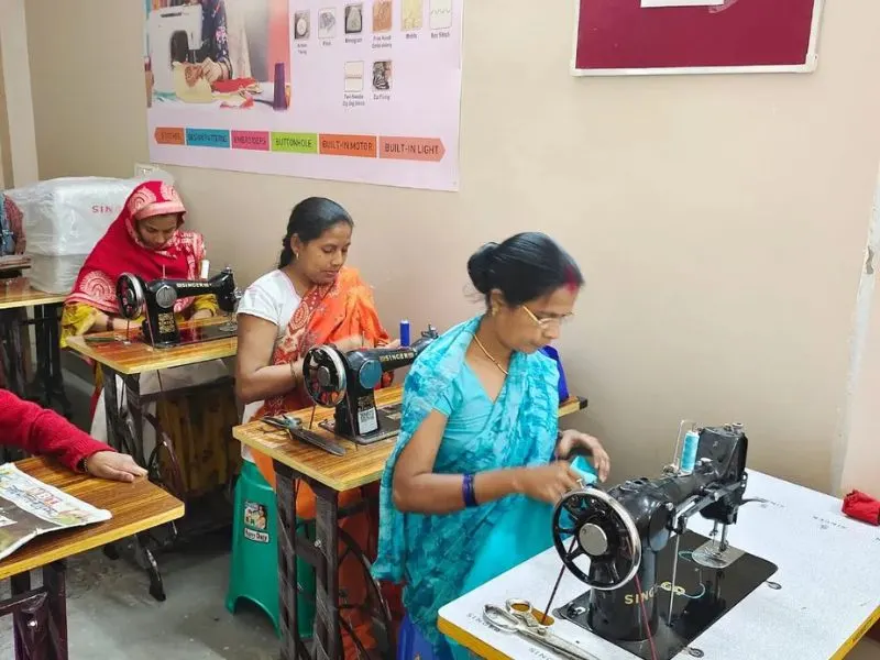 Women sewing at machines in a classroom, focused on their work